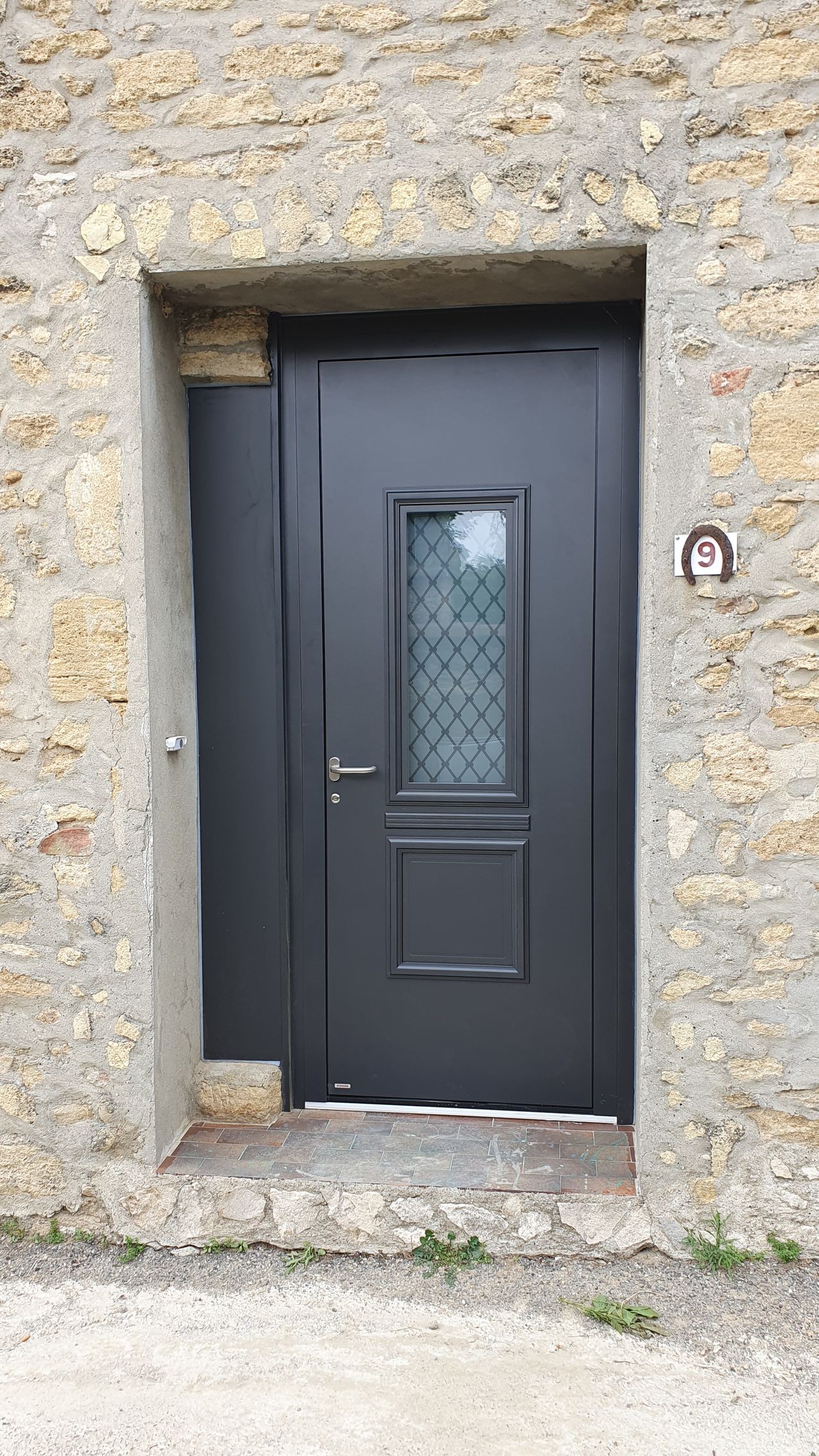 Porte d'entrée grise avec le vitrage.