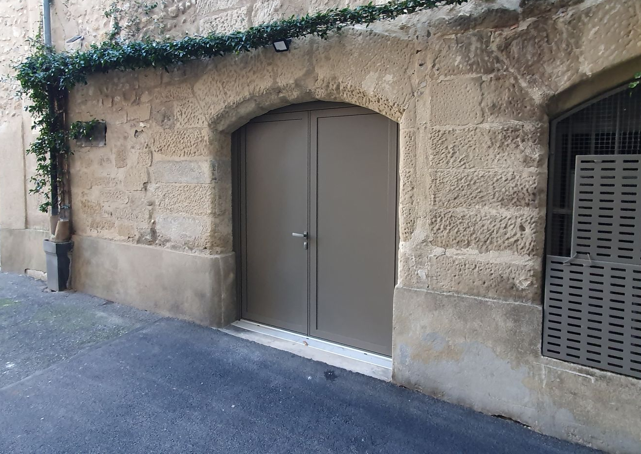 Porte de garage et façade en pierre.