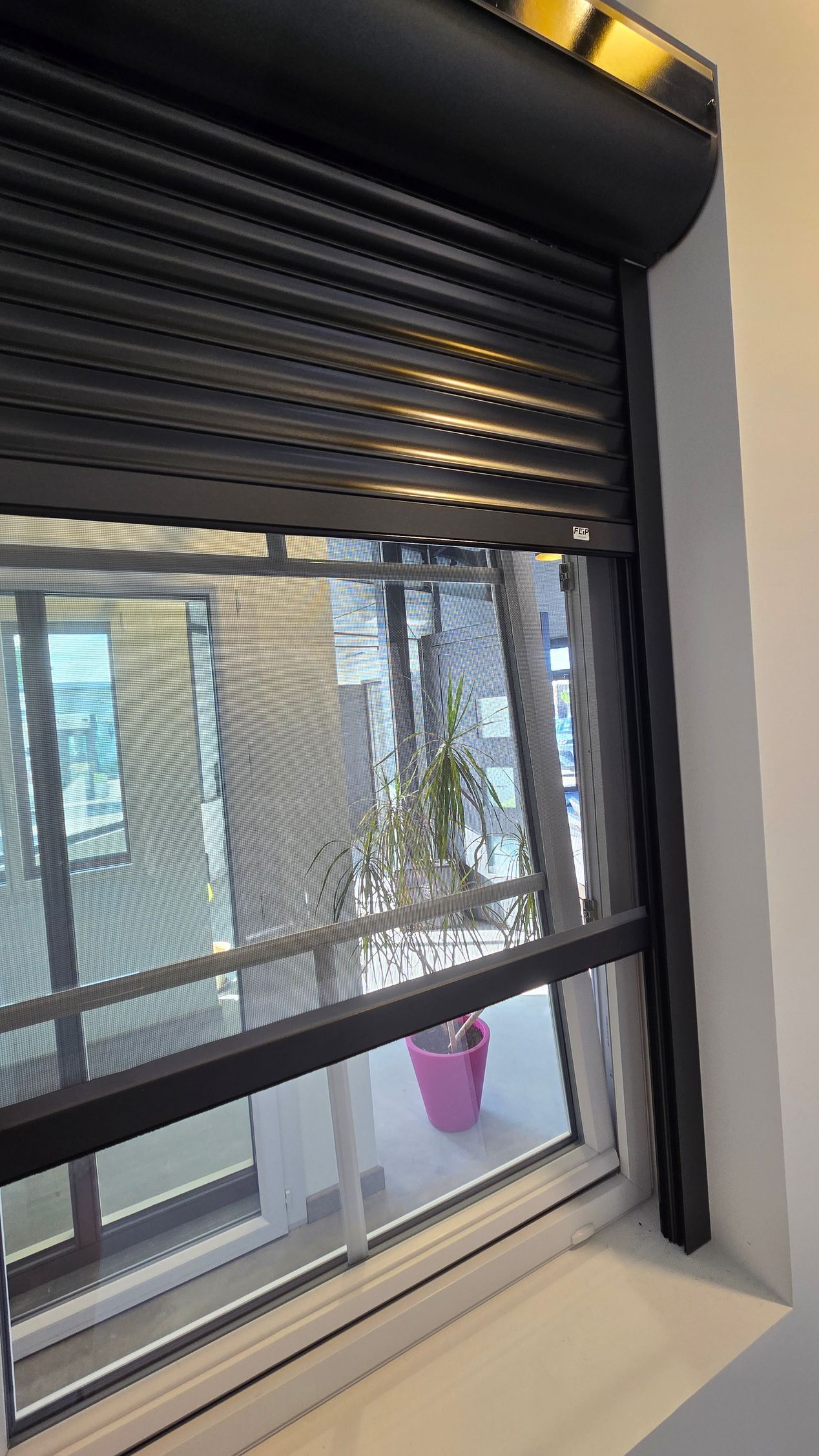 Gros plan sur la moustiquaire installée sur une fenêtre avec le volet roulant.