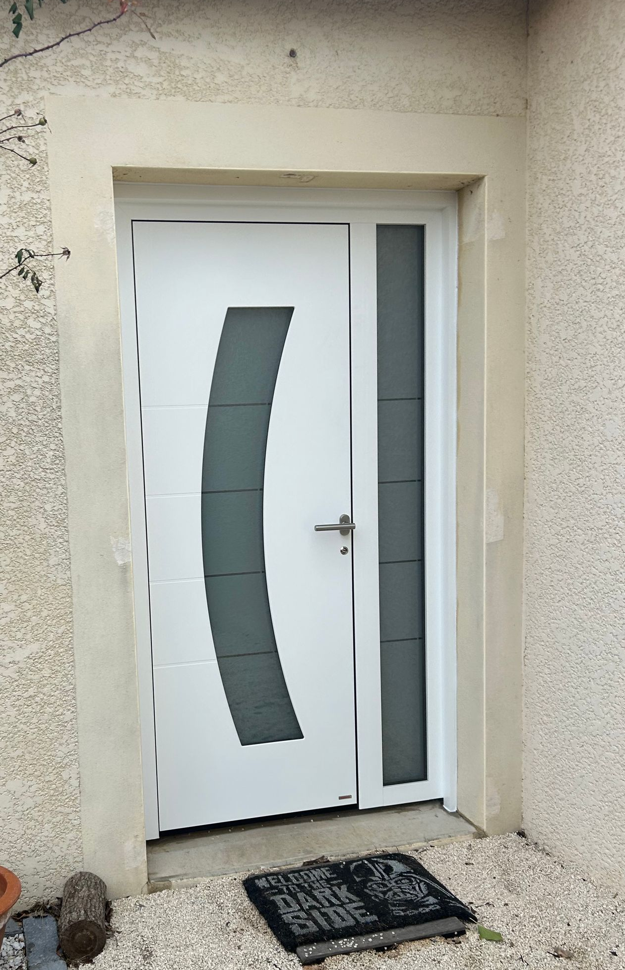 Une porte extérieure blanche avec le vitrage et un paillasson devant la porte.
