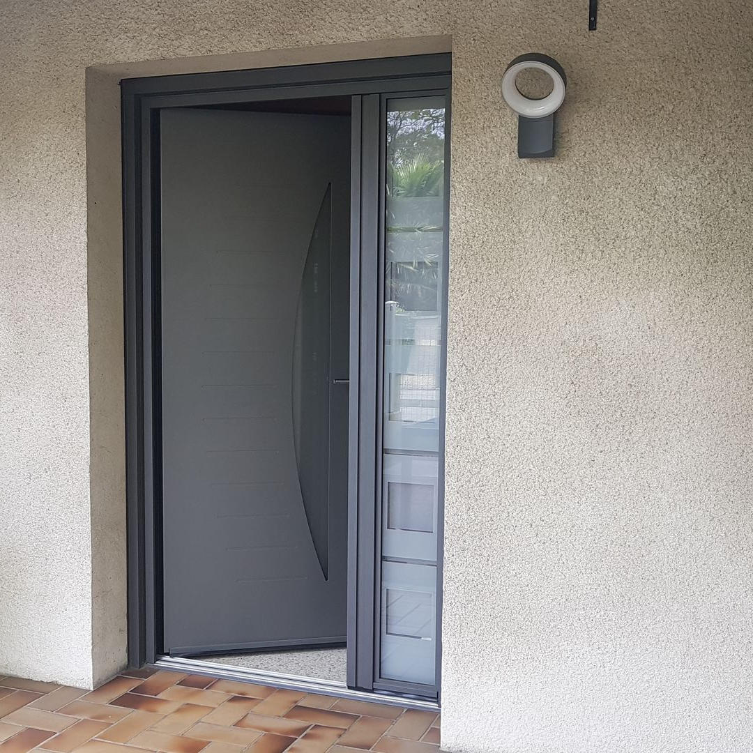 Une porte d'entrée moderne gris foncé avec un panneau de verre vertical, adjacente à une fenêtre latérale à rayures horizontales dépolies.