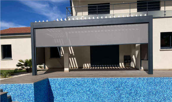 Pergola grise adossée à une maison avec une piscine vide en premier plan.