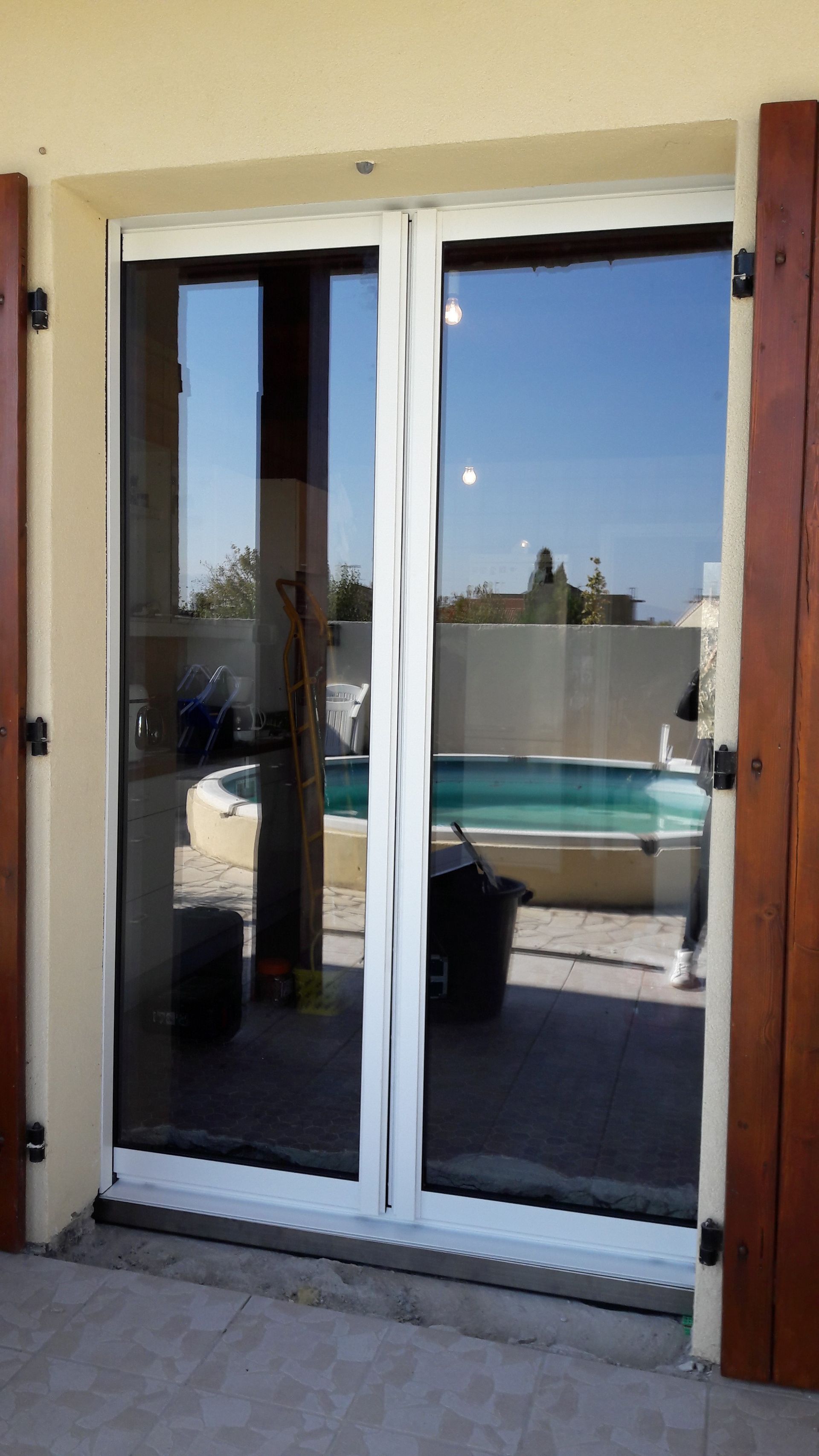 Des portes-fenêtres blanches doubles donnent sur une terrasse.