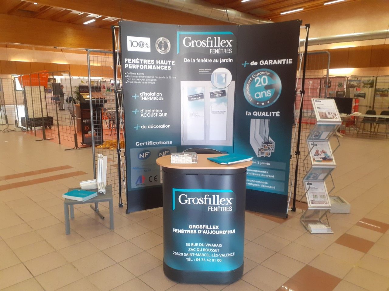 Un stand d'exposition pour les fenêtres Grosfillex, comprenant un pupitre d'information et un présentoir à brochures.