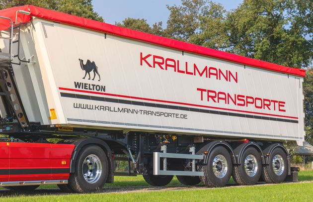 Ein rot-weißer Lastwagen steht vor einem Gebäude.