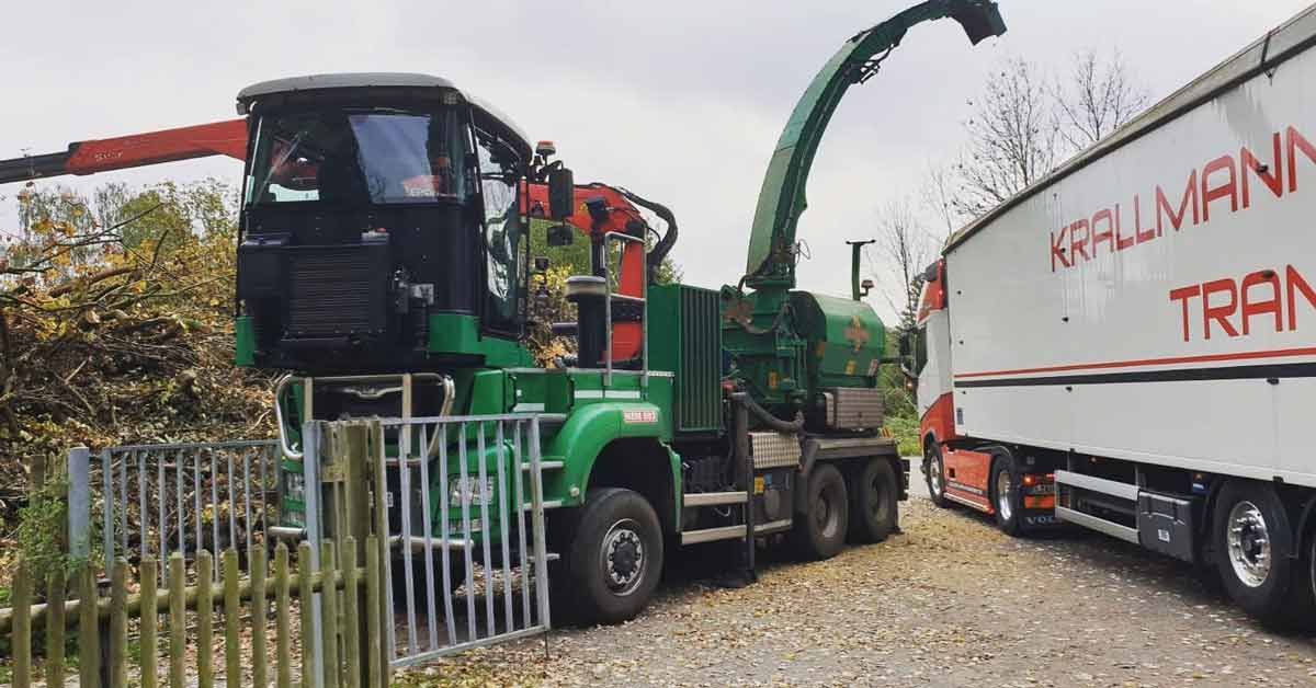 Ein LKW fährt auf einer unbefestigten Straße neben einem Traktor her.