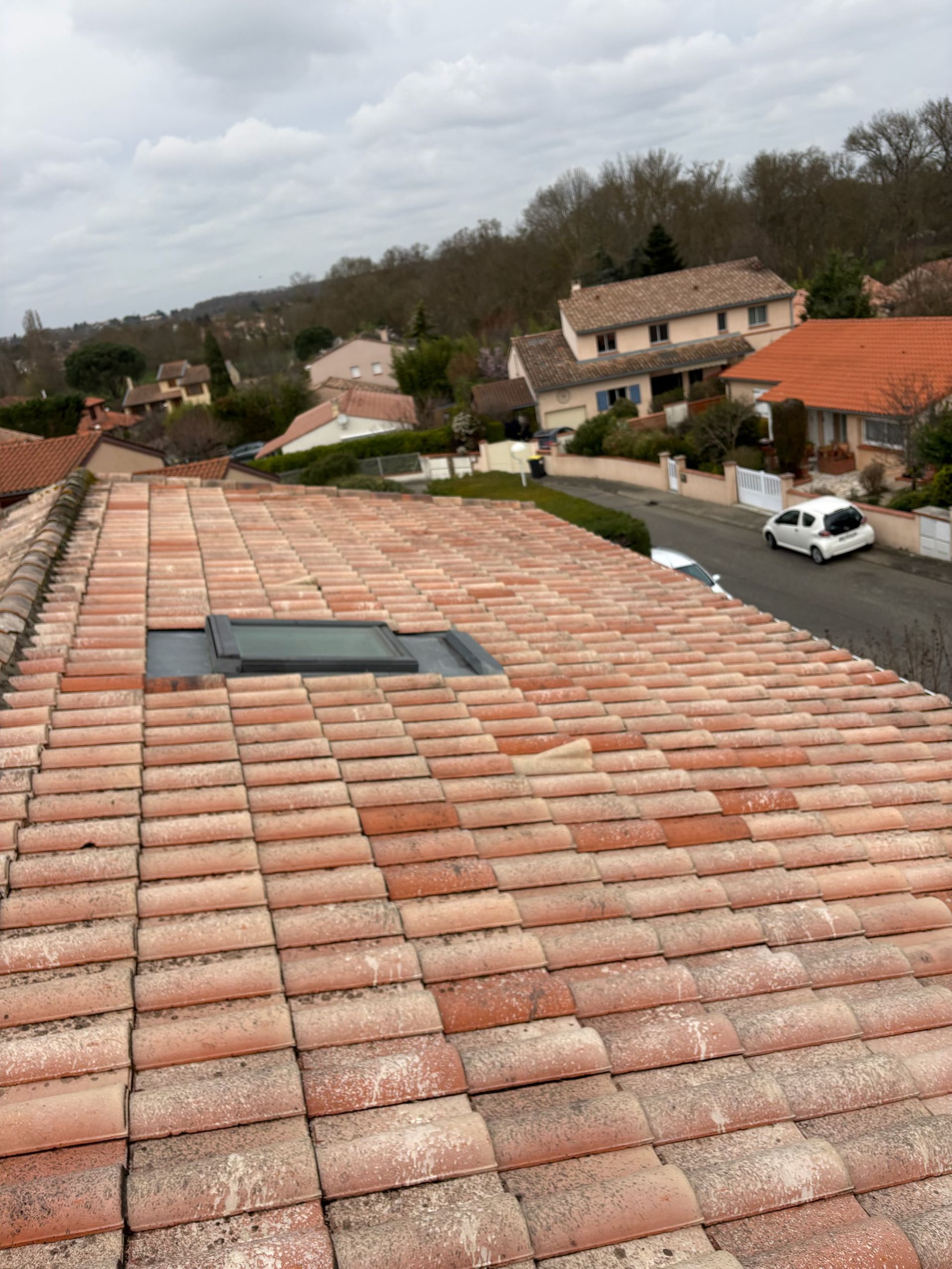 Vue depuis un toit de tuiles sur des maisons de banlieue et une rue de quartier nuageuse.