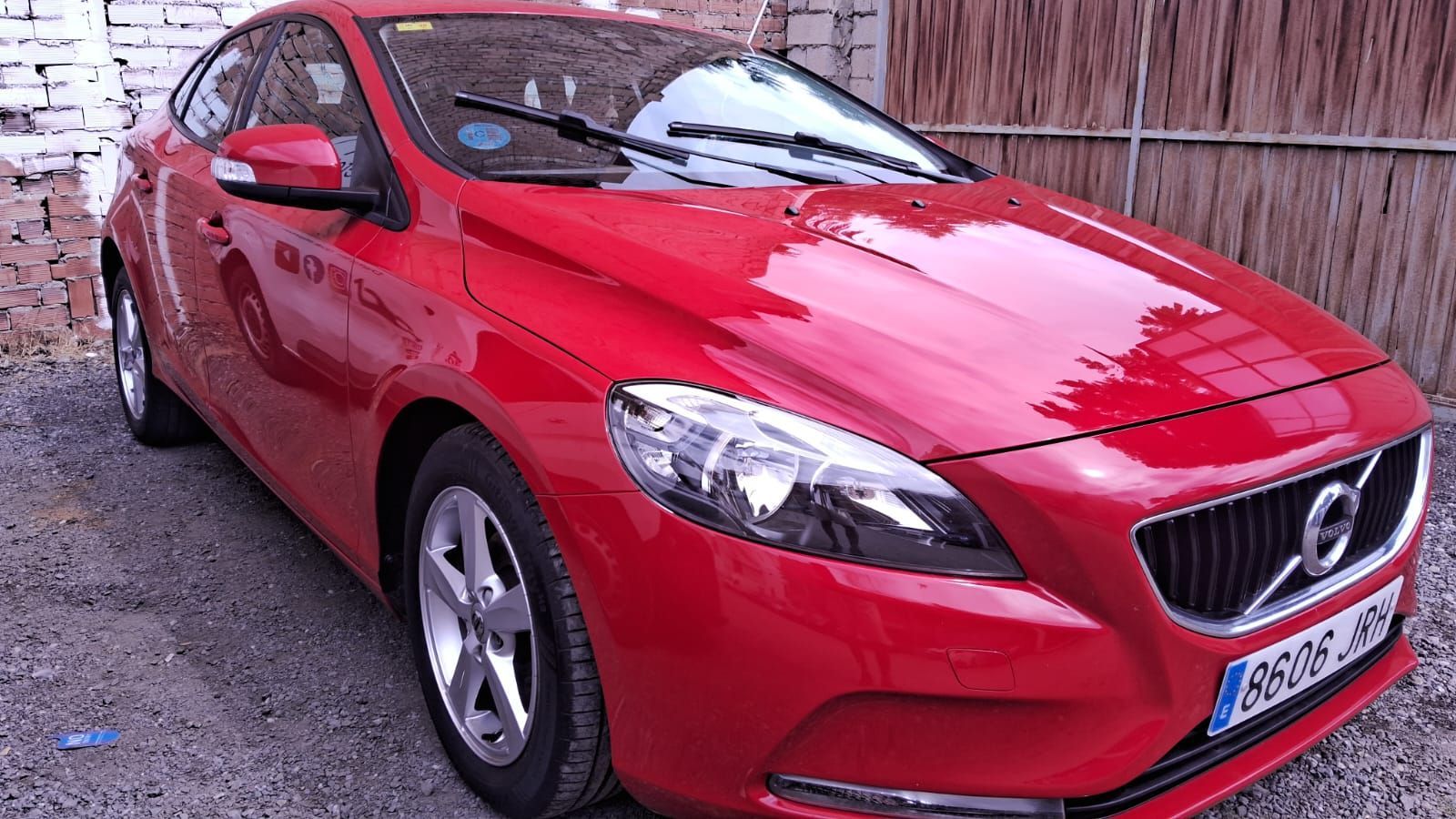Volvo V40 rojo estacionado en el exterior, sobre una superficie de grava.