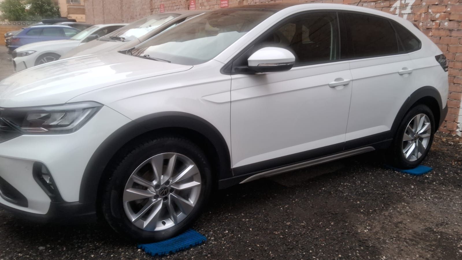SUV blanco estacionado sobre una superficie oscura, con molduras negras y ruedas plateadas.