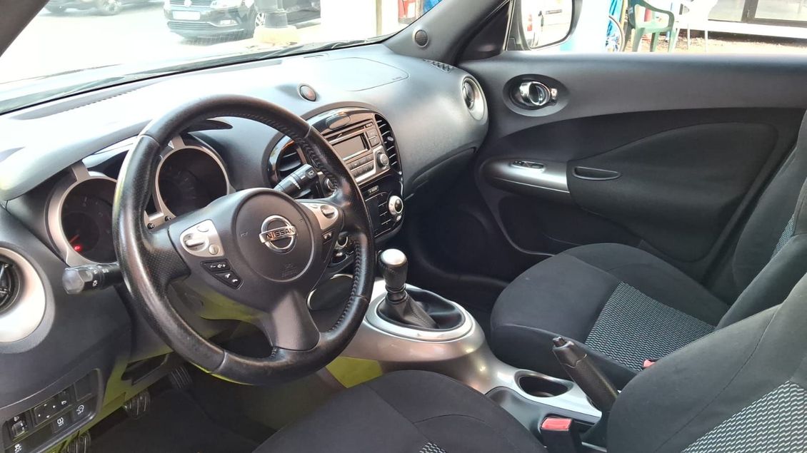 Vista interior de un Nissan Juke. Tablero, volante y asientos negros. Detalles plateados.