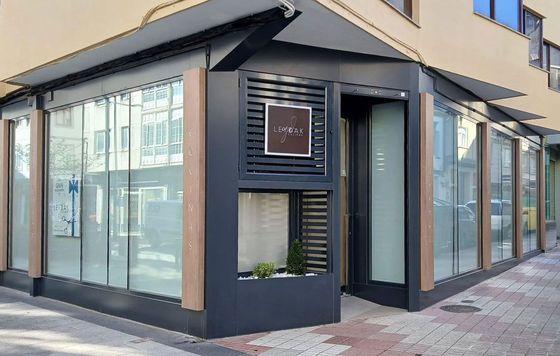 Vista exterior de esquina de un edificio moderno con grandes ventanales y fachada oscura.