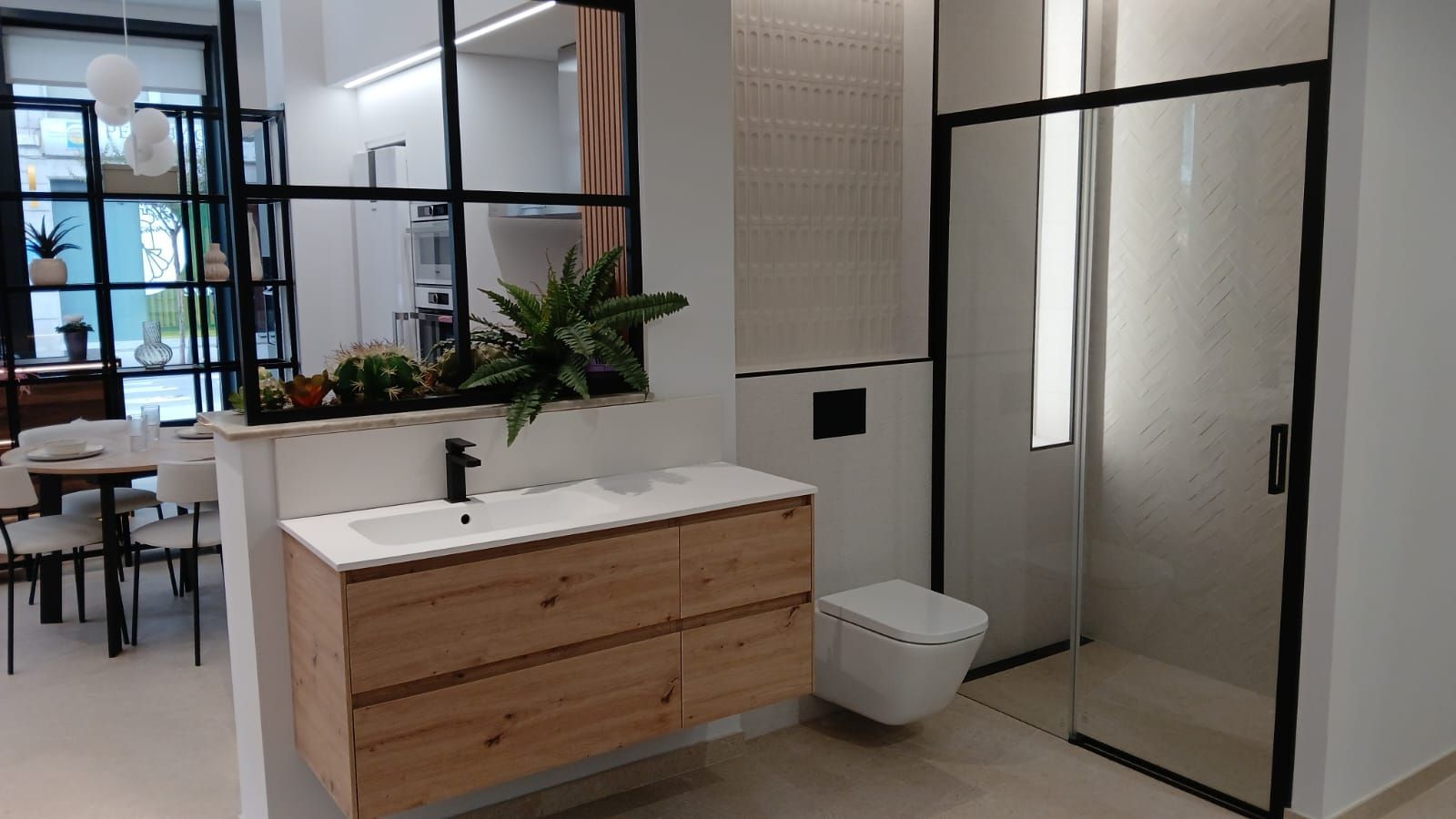 Baño moderno con tocador de madera, inodoro blanco y mampara de ducha de cristal.