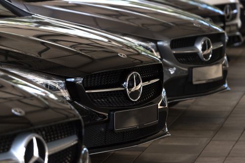 Rivi mustia Mercedes-Benz-autoja pysäköitynä sisälle, näkyy etusäleiköstä ja ajovaloista katsottuna
