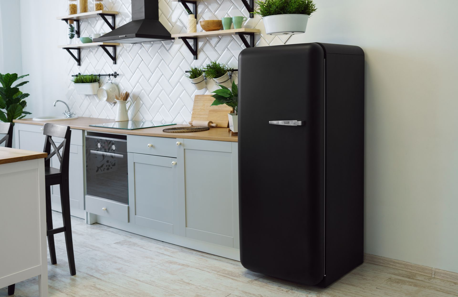 Réfrigérateur rétro noir dans une cuisine lumineuse avec des accents blancs et bois.