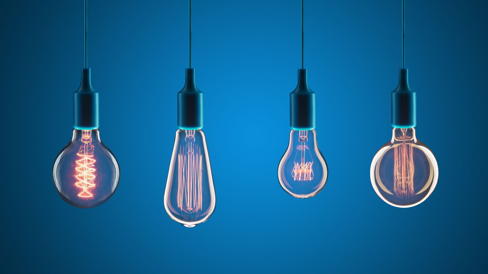 Quatre ampoules de style Edison allumées suspendues sur un fond bleu.