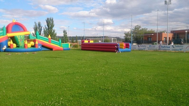 Un exuberante campo verde con un castillo inflable al fondo