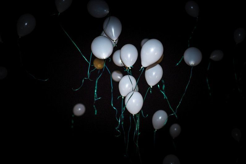 Un montón de globos blancos vuelan en la oscuridad.