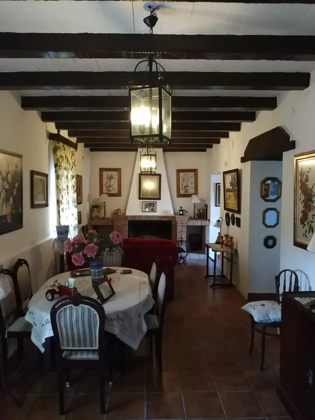 Comedor con mesa puesta, chimenea y vigas de madera a la vista.