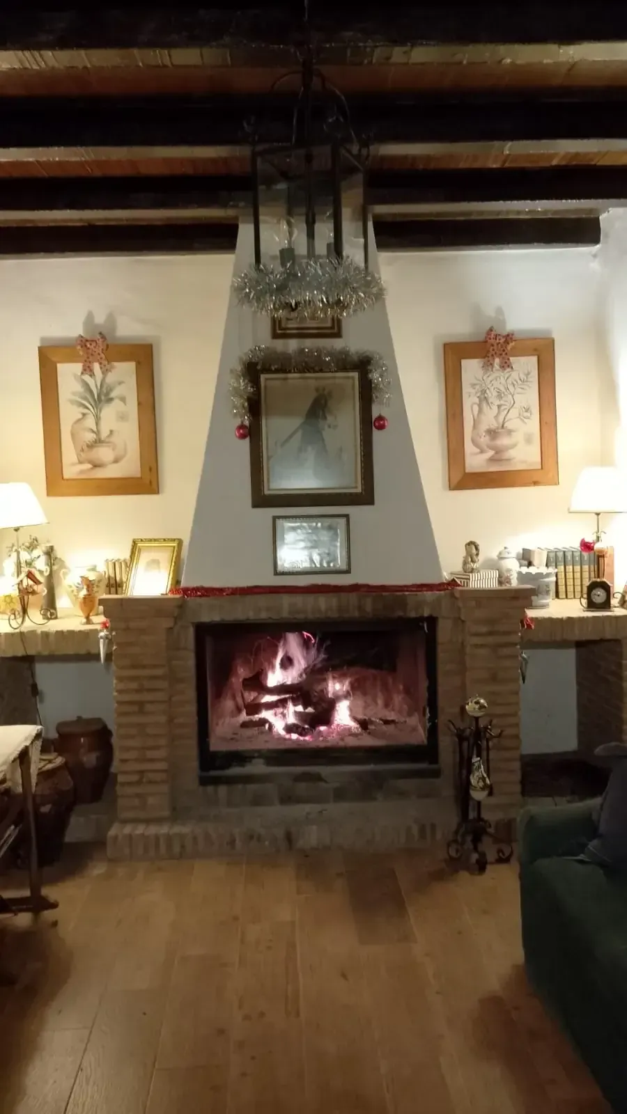 Acogedora sala de estar con chimenea encendida, obras de arte enmarcadas y vigas de madera.