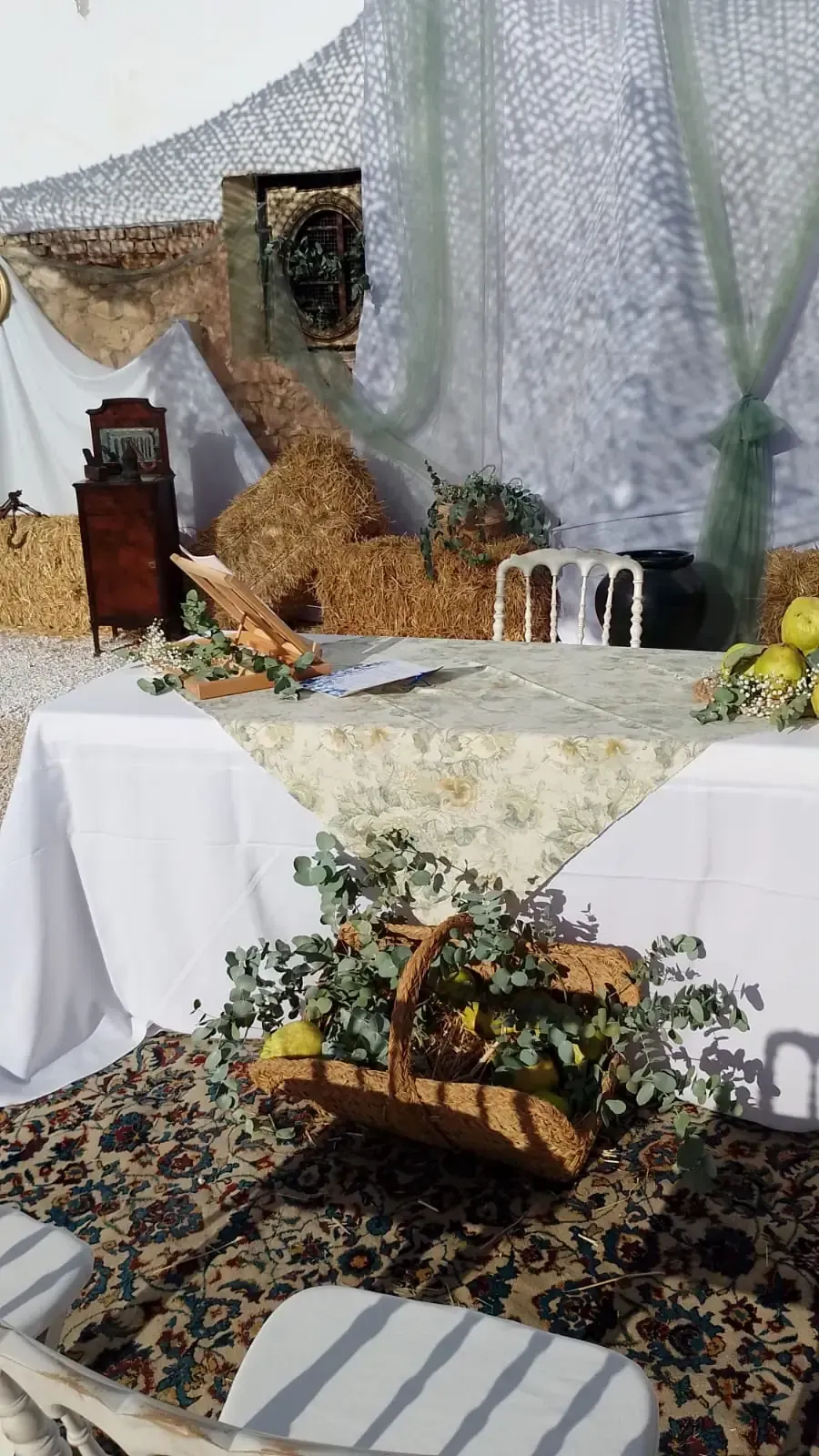 Mesa de recepción de boda decorada con limones, vegetación y canasta tejida, sobre un fondo de tela.
