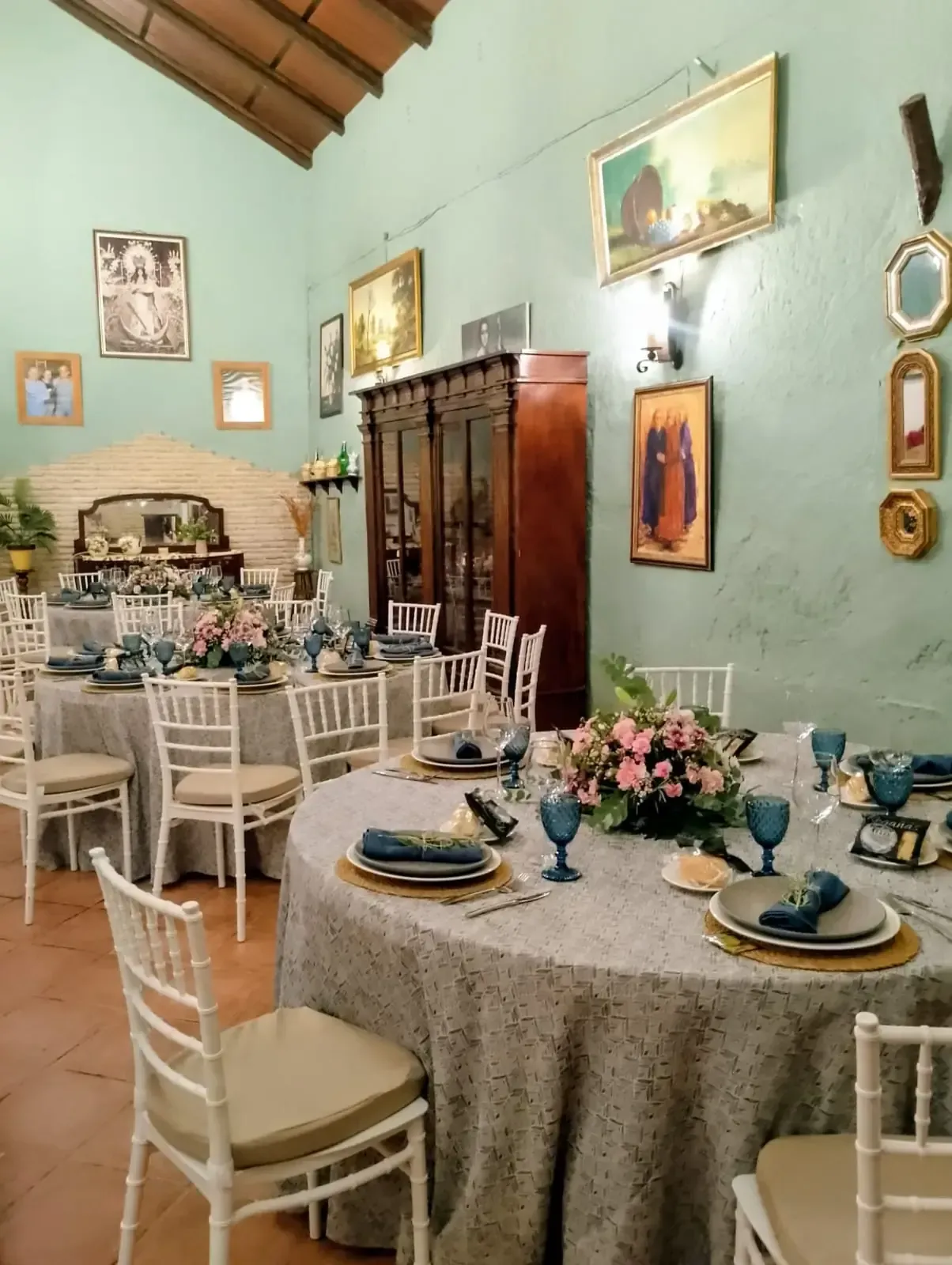 Mesas redondas dispuestas para una reunión en una sala con decoración vintage y arte en las paredes.