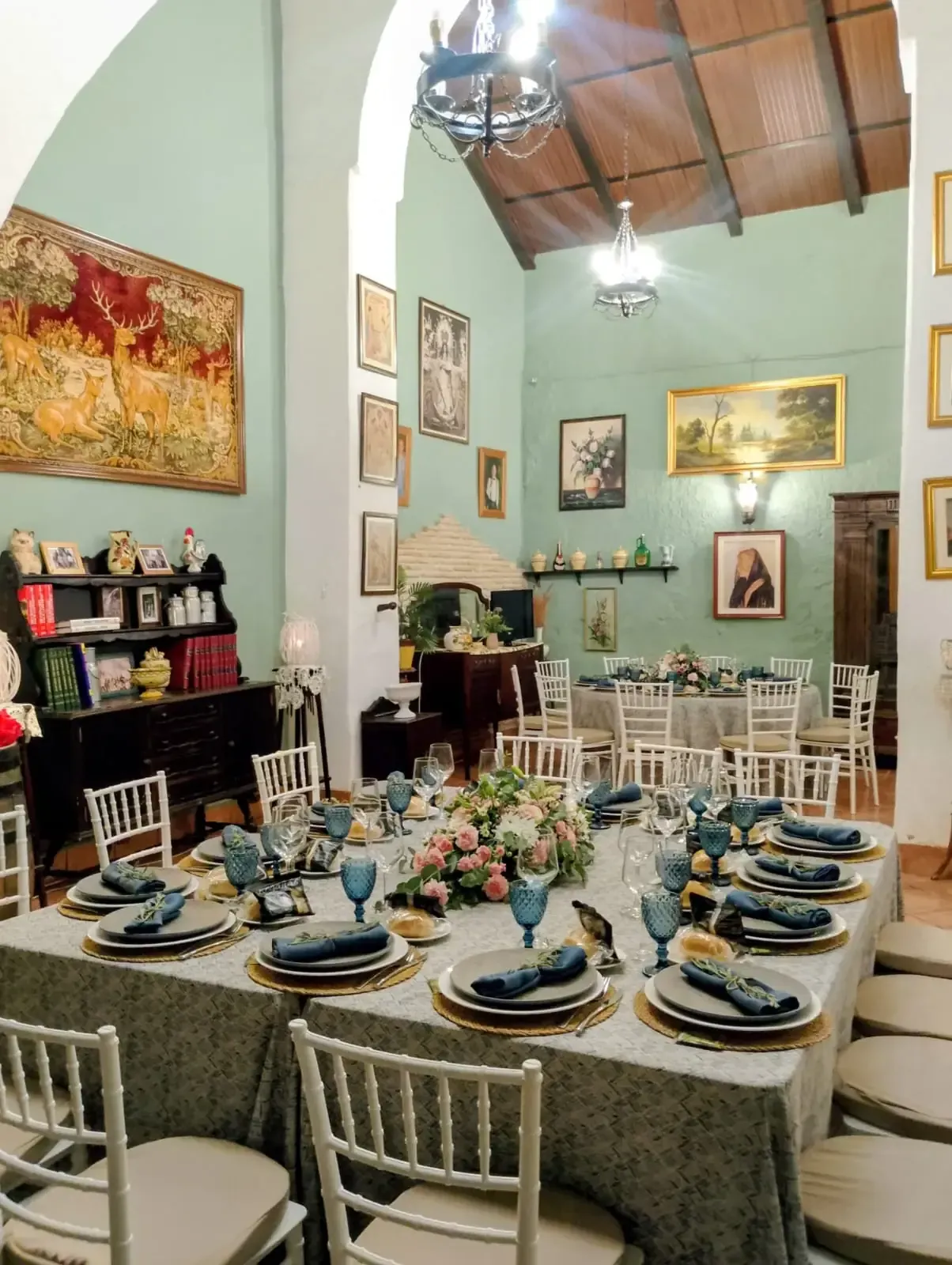 Elegante comedor para una comida. Mesa larga, decoración ornamentada, sillas y vajilla. Paredes verde claro.