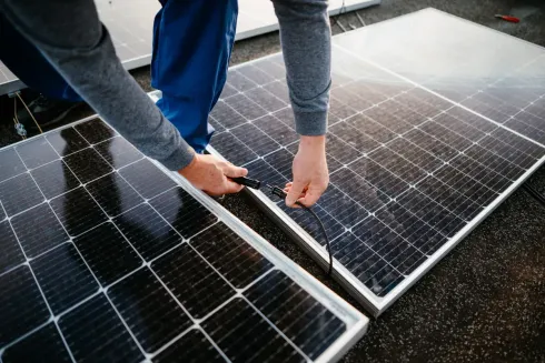 Persona conectando paneles solares en un tejado.