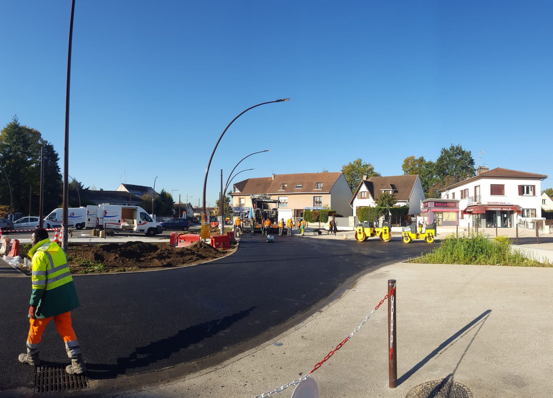 Des ouvriers du bâtiment effectuent des travaux de pavage sur un rond-point par une journée ensoleillée.