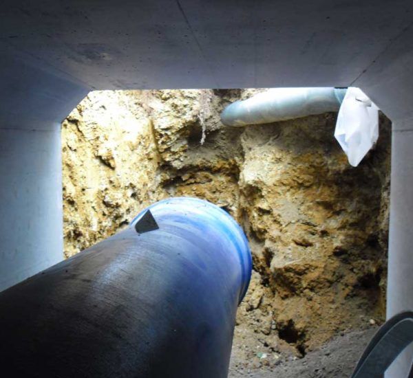 Regard vers le haut, à l'intérieur d'un trou creusé à même la terre et rempli de tuyaux.