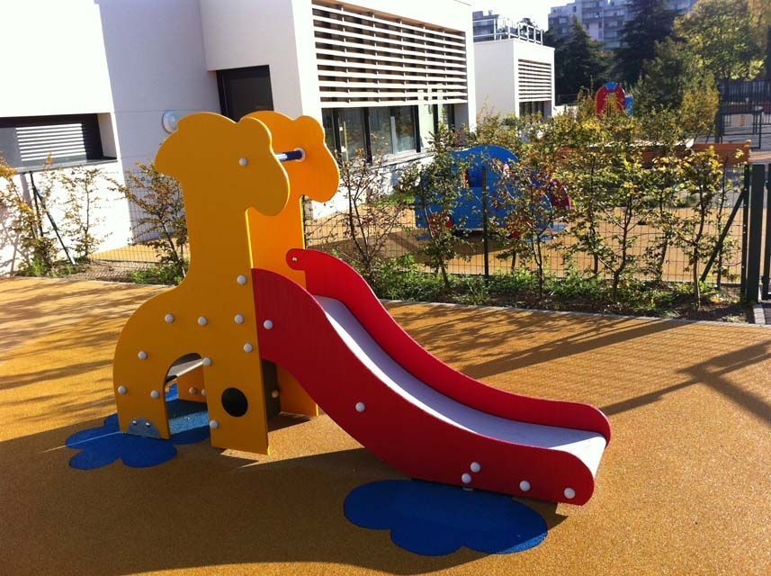Toboggan jaune en forme de girafe avec toboggan rouge, dans une aire de jeux.