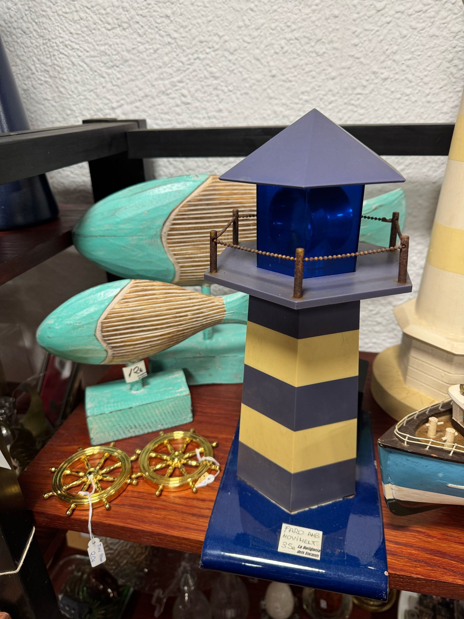 Un faro azul y amarillo está sentado encima de una mesa de madera.