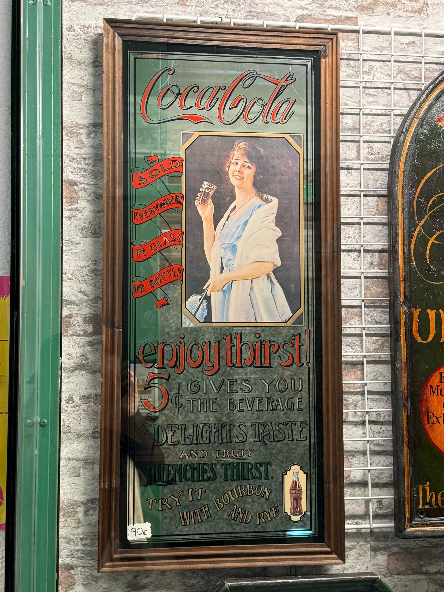 Una foto de una mujer sosteniendo un vaso de Coca Cola en un espejo.