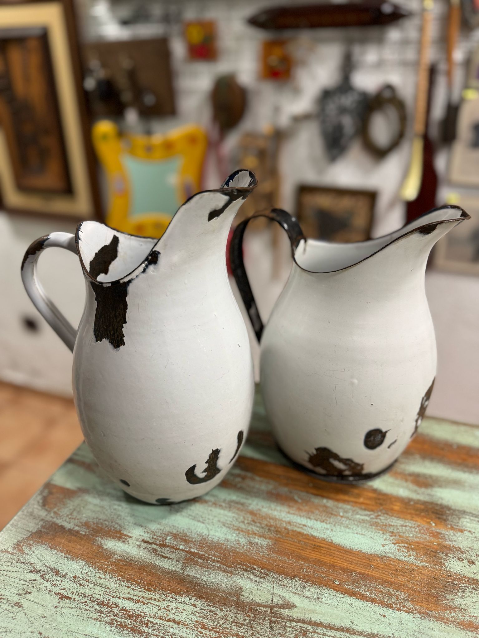 Dos jarras blancas con asas negras están sobre una mesa de madera.