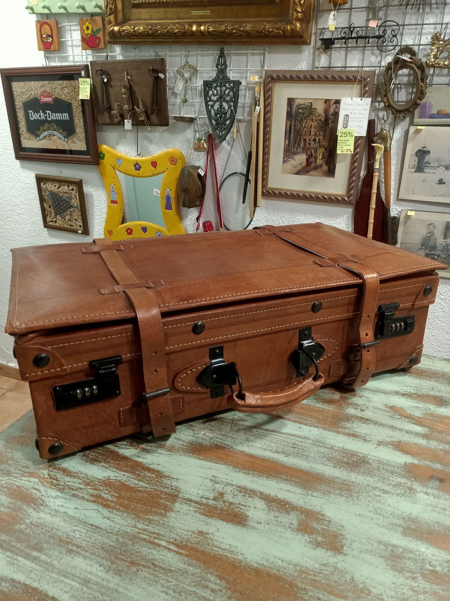 Una gran maleta de cuero marrón está sobre un suelo de madera.