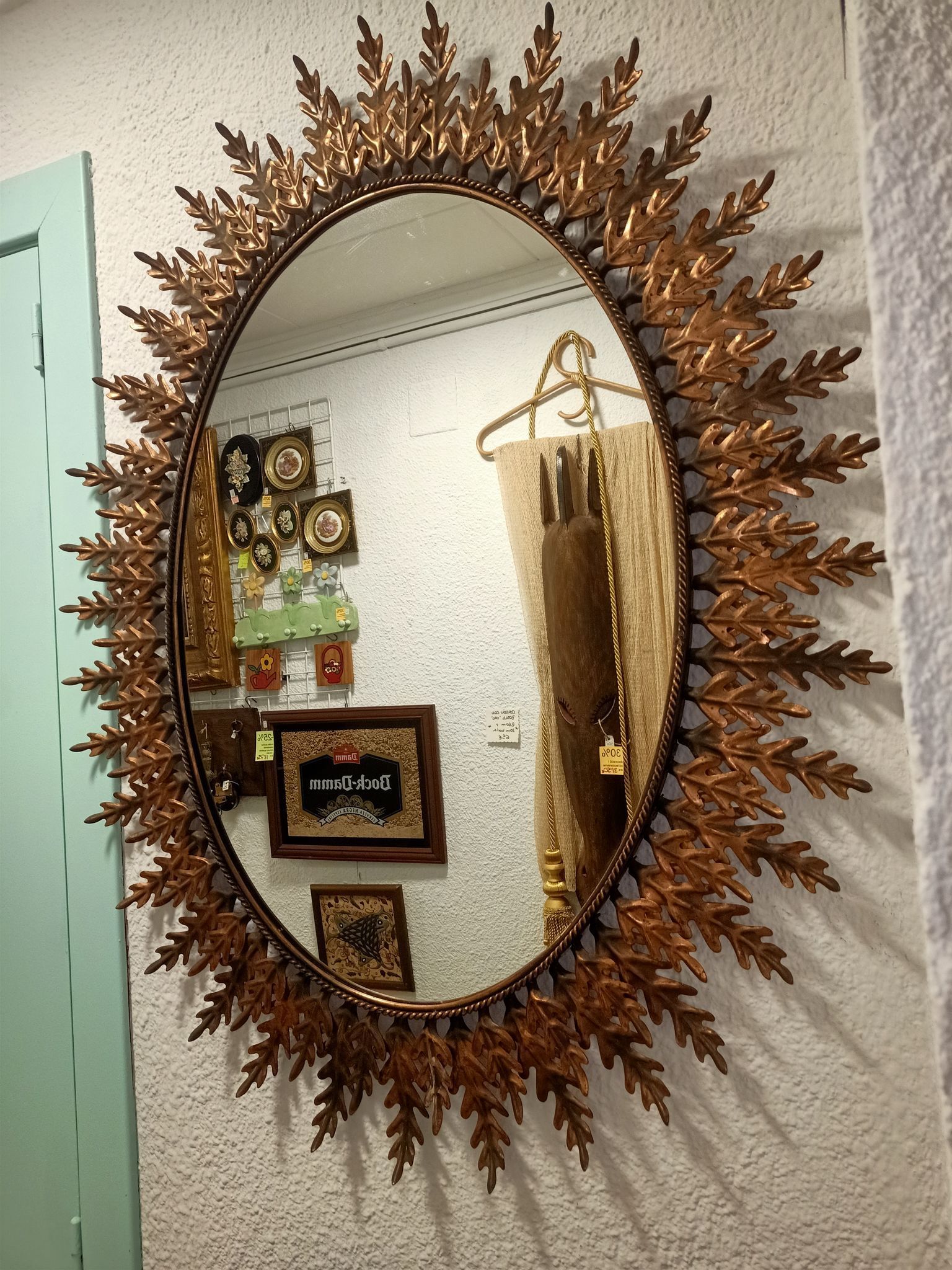 Un espejo grande con marco en forma de sol está colgado en una pared.