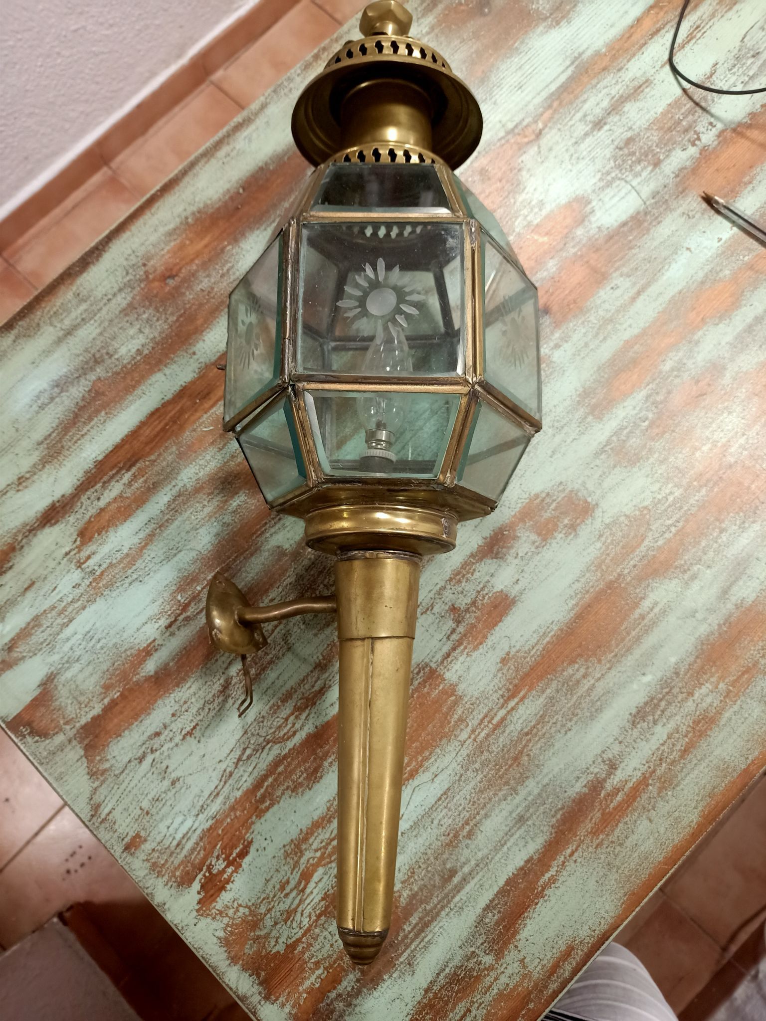 Una linterna de latón reposa sobre una mesa de madera.