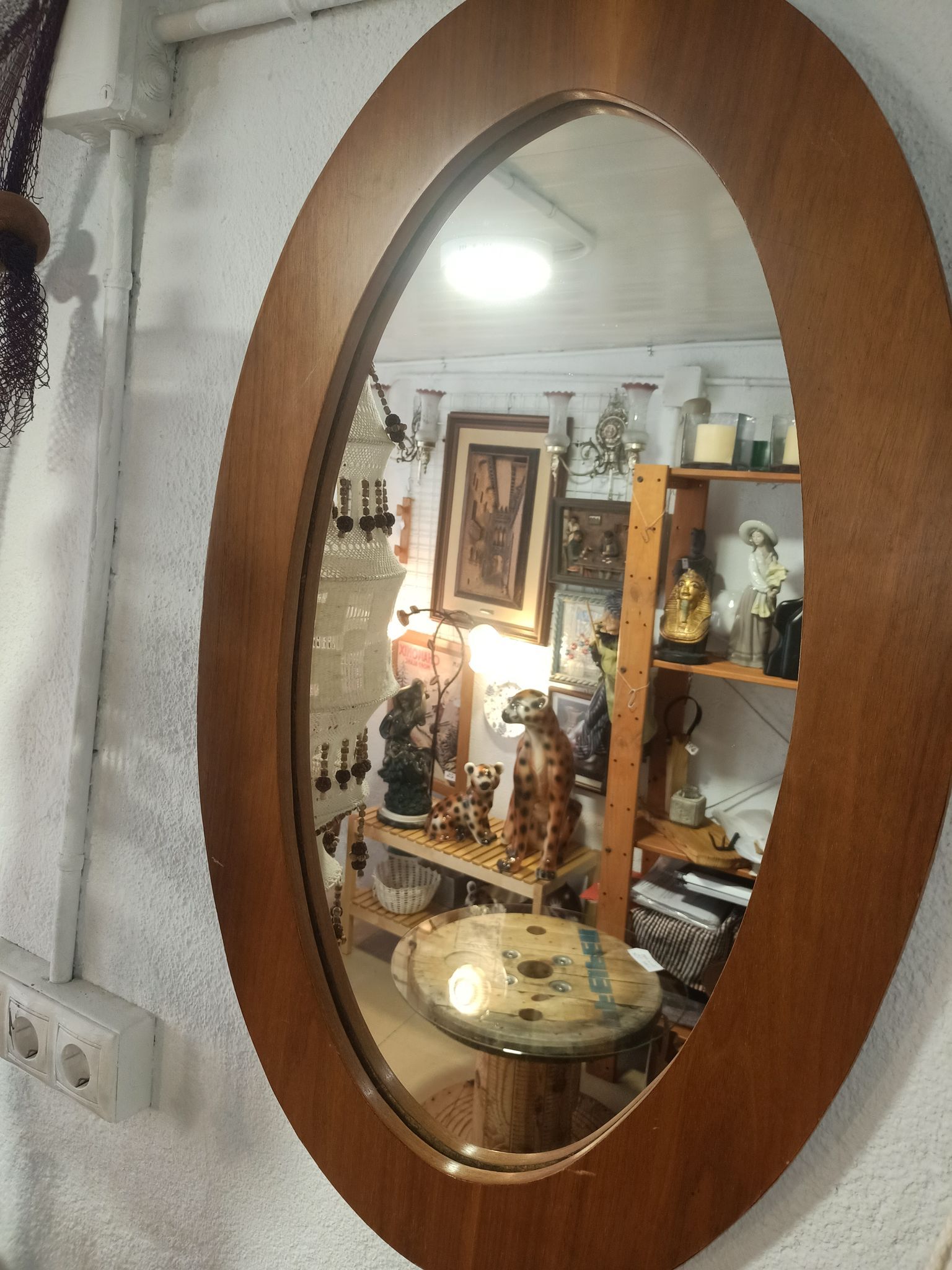 Un espejo ovalado con marco de madera está colgado en una pared.