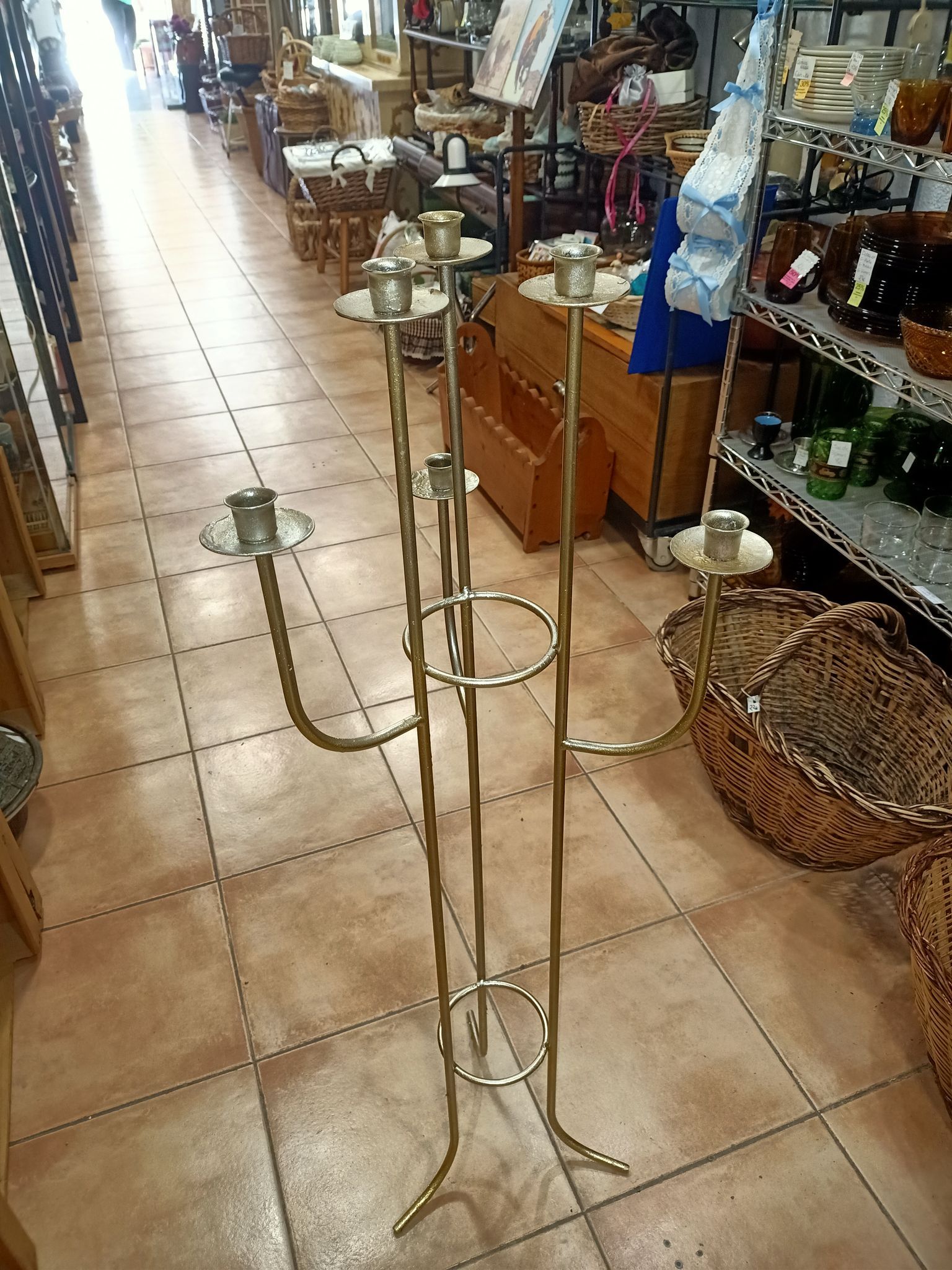 Un candelabro de latón reposa sobre un suelo de baldosas en una tienda.