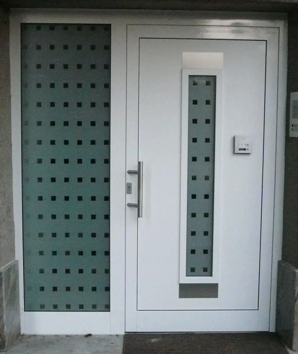 Weiße Tür mit Milchglasplatten und Quadraten. Silberner Griff und Briefkasten.