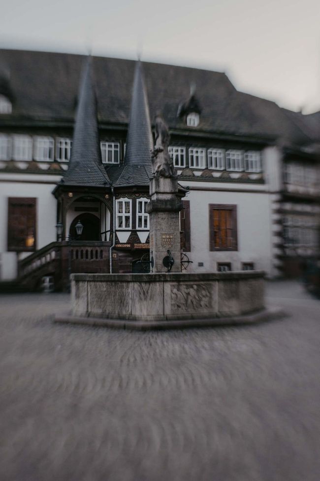 Vor einem großen Gebäude steht ein Brunnen.