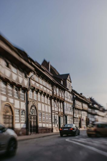 Ein verschwommenes Bild von Autos, die vor einem Gebäude eine Straße entlangfahren.