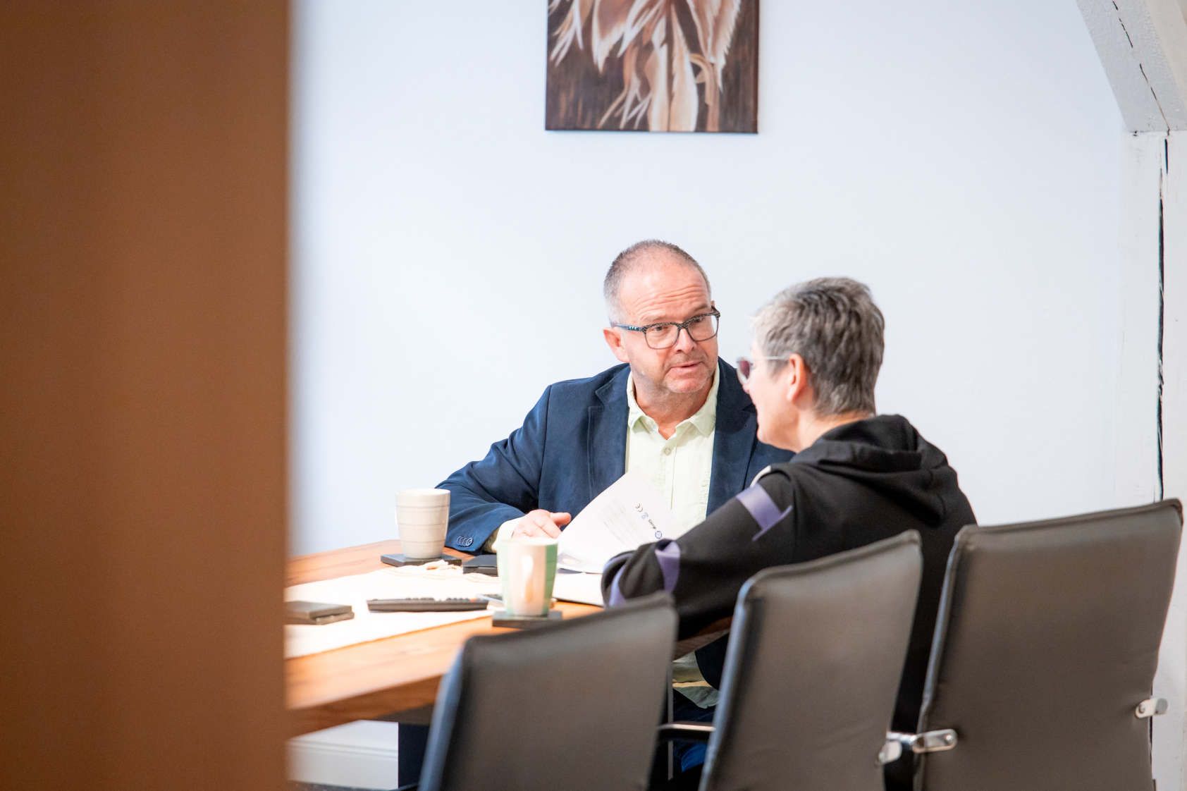 Ein Mann und eine Frau sitzen an einem Tisch und unterhalten sich.