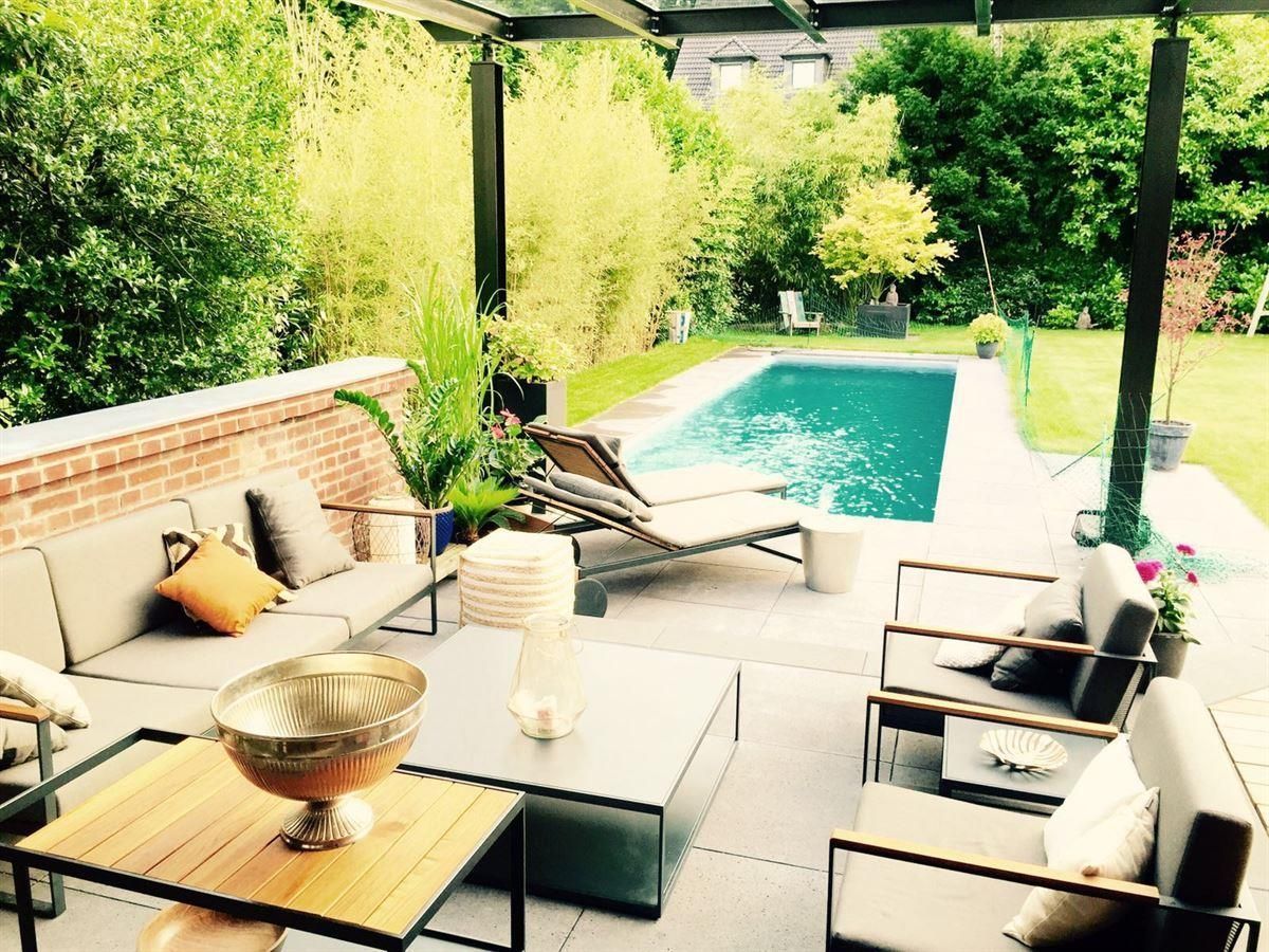 Ein Terrassenbereich mit einem Swimmingpool im Hintergrund