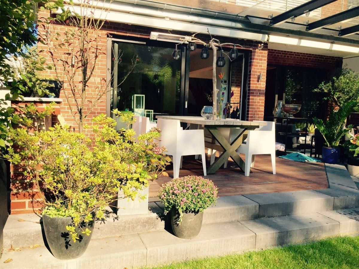 Eine Terrasse mit Tisch und Stühlen vor einem Backsteingebäude.