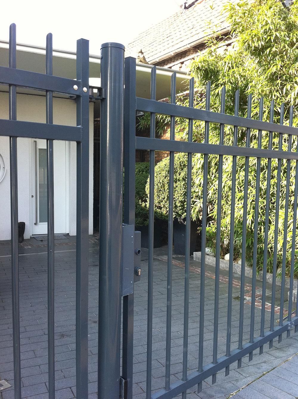 Ein schwarzer Metallzaun umgibt ein weißes Haus