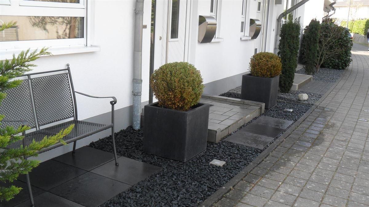 Auf dem Bürgersteig vor einem Haus steht eine Bank.