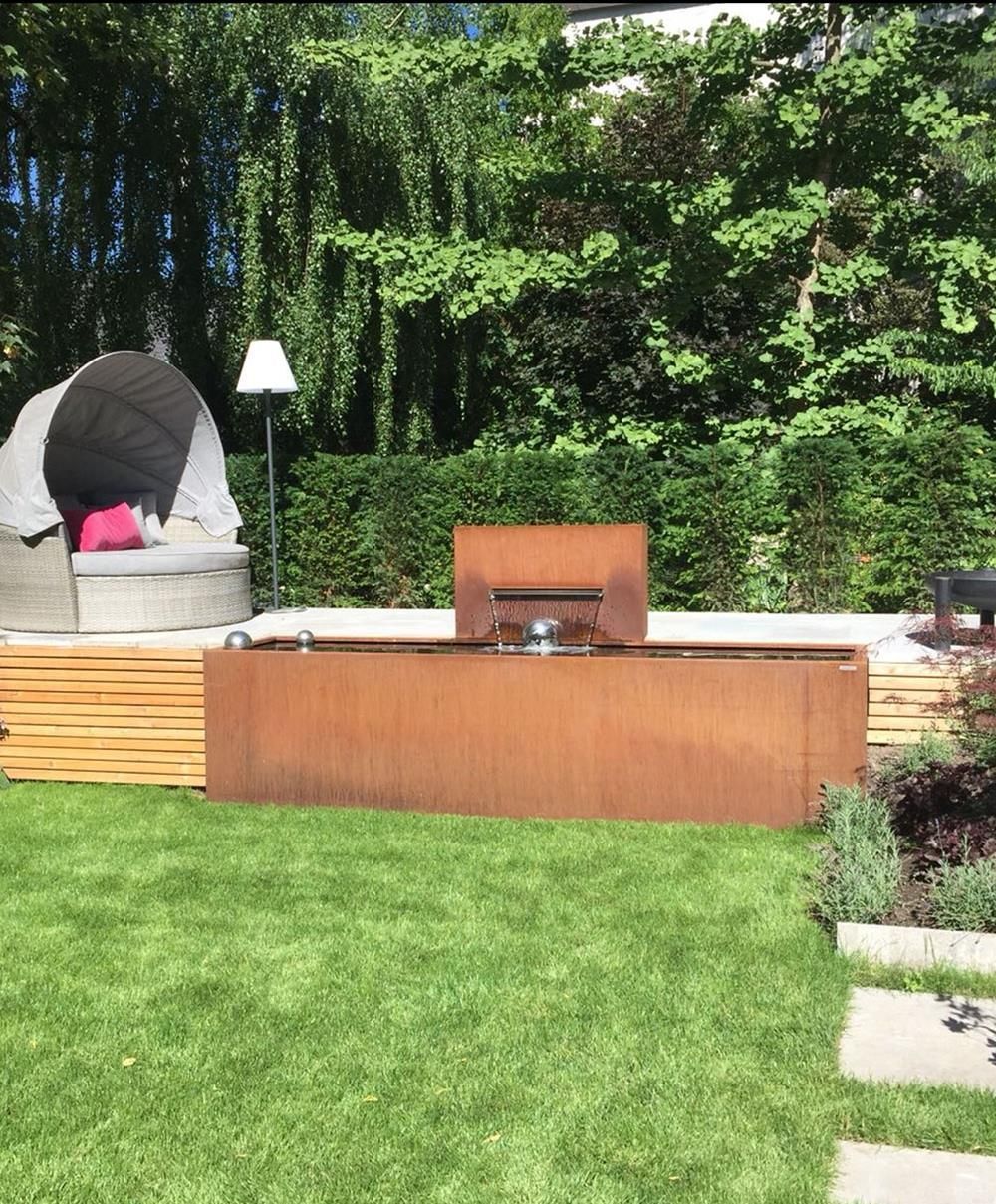 Ein großer Holztisch steht inmitten eines üppig grünen Hofes.