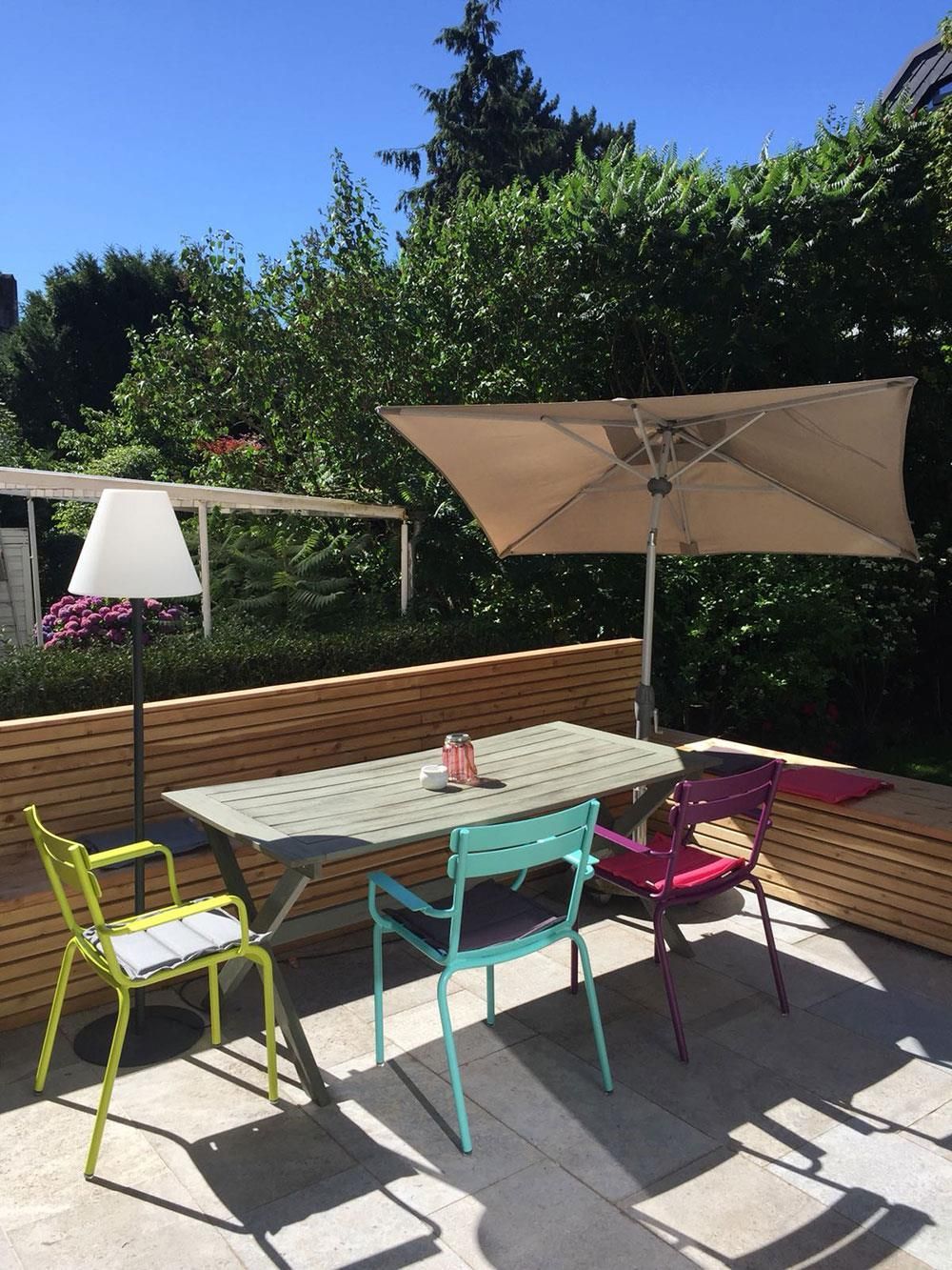 Eine Terrasse mit Tisch und Stühlen unter einem Sonnenschirm