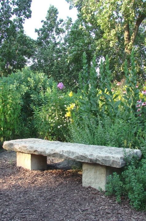 Eine Steinbank steht mitten in einem Garten
