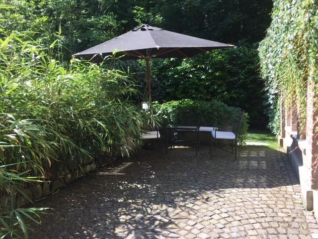 Eine Terrasse mit Tisch und Stühlen unter einem Sonnenschirm